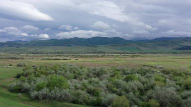 Yeşil alanlar ve nehir. Dağlar ufukta görünür