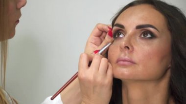 Fırça ile Makyaj sanatçısı kızın yüzüne gölgeler koyar.