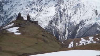 Gergeti Trinity Kilisesi karla kaplı dağların arka planında: Gürcistan'ın en kutsal yerlerinden biri- gergeti dağındaki antik tapınak
