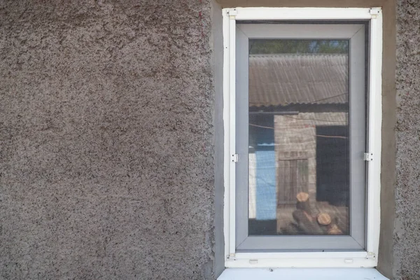 Duvardaki plastik pencere. Pencere kırsal avludaki elementleri yansıtıyor.