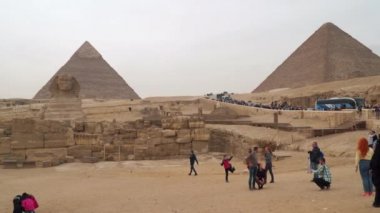 Giza , Egypt - January 14, 2020 : Great Sphinx on the west bank of the Nile in Giza . In the background is the Cheops Pyramid and the Chephren Pyramid