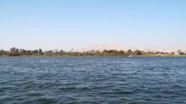 The coast of the Nile River near the city of Luxor in Egypt. You can see floating tourist boats, mountains are visible on the horizon. Shooting with a floating boat