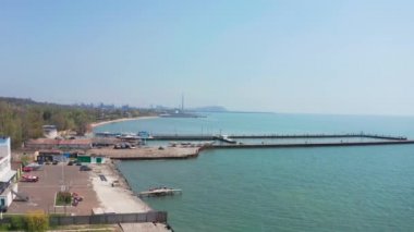 Deniz kıyısı. Hava görüntüsü. Mariupol Ukrayna. Ufukta deniz iskelesini yatlarla, uçan martılarla görebilirsiniz. Ufukta metalürjik bir bitki var.