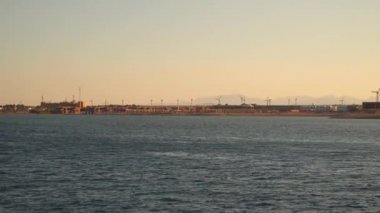 Kıyıda rüzgar türbinleri. Gemiden deniz manzarası. Akşam vakti. Kızıl deniz. Mısır.