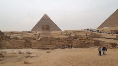 Giza, Mısır - 14 Ocak 2020: Khafre piramidinin arka planında büyük sfenks. Sfenksin yüzünün genellikle firavun Khafre 'yi temsil ettiğine inanılır.