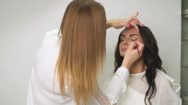 Makyaj yapma süreci. Makyaj sanatçısı model yüzünü fırçalarken, kadın güzellik salonunda. Profesyonel makyaj. İş sırasında profesyonel makyaj sanatçısı.