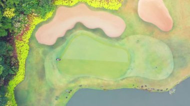 Golf sahasının çimlerini kesen bir adamın hava görüntüsü.