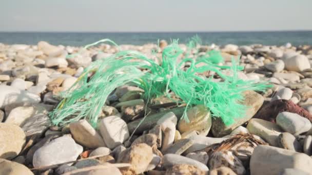 Кусок пластиковой веревки, лежащий над галечными камнями на берегу моря — стоковое видео