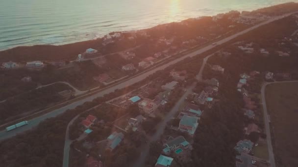Zdjęcia lotnicze droga i domy w pobliżu nabrzeża ze słońcem — Wideo stockowe