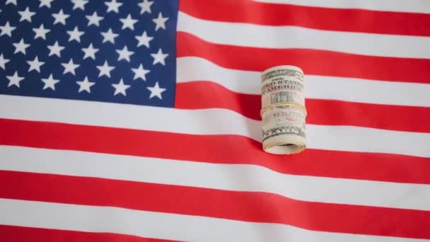 Рулон денег, лежащий над американским флагом — стоковое видео