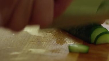 Bir insan bıçakla salatalığı dilimliyor.