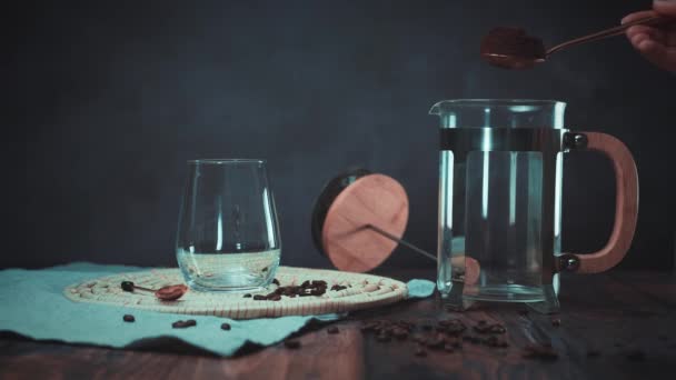 Person pouring a spoon of black coffee powder in coffee press — Stock Video