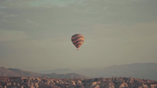 Balon na gorące powietrze przelatujący nad pustynnymi wzgórzami i górami — Wideo stockowe