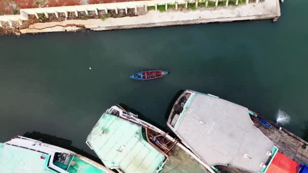 Liten motorbåt som rör sig förbi stora fiskebåtar i en hamn — Stockvideo