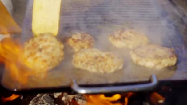 Using a spatula to flip burgers on a smoke fire grill top — Stock Video