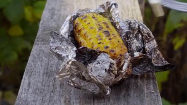 Izgarada folyoda pişmiş mısır. İleriye doğru kayıyor. Yakın plan.