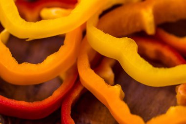 Tahta bir masada dilimlenmiş portakal, kırmızı ve sarı dolma biber.