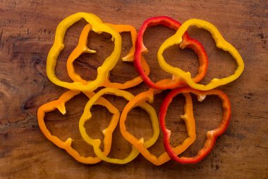 Tahta bir masada dilimlenmiş portakal, kırmızı ve sarı dolma biber.