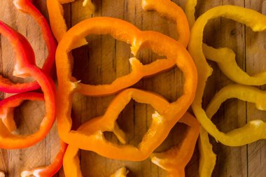 Tahta bir masada dilimlenmiş portakal, kırmızı ve sarı dolma biber.