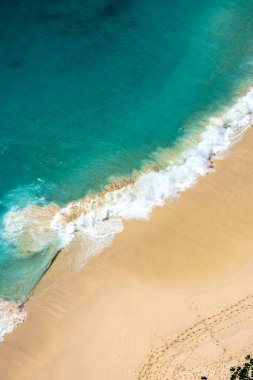 Okyanus manzaralı, kumlu sahilde dalgalar kırılıyor. Okyanus suyu tropikal mavi. 