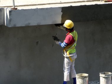 Kuala Lumpur, Malezya-23 Temmuz 2018: inşaat işçileri çimento kullanarak duvar sıvama alçı inşaat alanında. Onlar kötü olmasını önlemek için uygun güvenlik dişli giyiyorsun.  