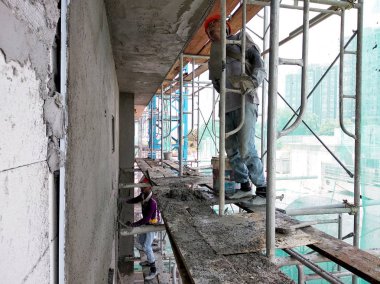 Kuala Lumpur, Malezya-23 Temmuz 2018: inşaat işçileri çimento kullanarak duvar sıvama alçı inşaat alanında. Onlar kötü olmasını önlemek için uygun güvenlik dişli giyiyorsun.  