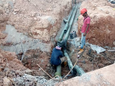 Kuala Lumpur, Malezya-02 Haziran 2017: inşaat alanında sığ siperlerde yeraltı yardımcı ve hizmet boru yükleme Işçiler. Kaynak yöntemi kullanılarak boru eklem montajı.    