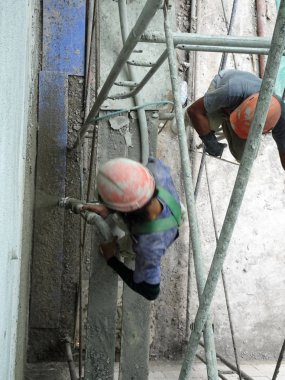 Kuala Lumpur, Malezya-23 Temmuz 2018: inşaat işçileri çimento kullanarak duvar sıvama alçı inşaat alanında. Onlar kötü olmasını önlemek için uygun güvenlik dişli giyiyorsun.  