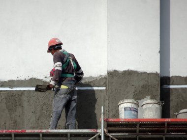 Kuala Lumpur, Malezya-23 Temmuz 2018: inşaat işçileri çimento kullanarak duvar sıvama alçı inşaat alanında. Onlar kötü olmasını önlemek için uygun güvenlik dişli giyiyorsun. 