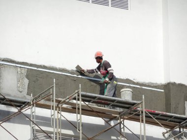Kuala Lumpur, Malezya-23 Temmuz 2018: inşaat işçileri çimento kullanarak duvar sıvama alçı inşaat alanında. Onlar kötü olmasını önlemek için uygun güvenlik dişli giyiyorsun. 