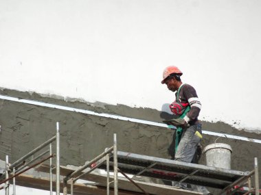 Kuala Lumpur, Malezya-23 Temmuz 2018: inşaat işçileri çimento kullanarak duvar sıvama alçı inşaat alanında. Onlar kötü olmasını önlemek için uygun güvenlik dişli giyiyorsun. 