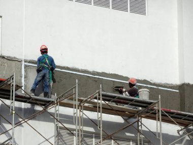 Kuala Lumpur, Malezya-23 Temmuz 2018: inşaat işçileri çimento kullanarak duvar sıvama alçı inşaat alanında. Onlar kötü olmasını önlemek için uygun güvenlik dişli giyiyorsun. 