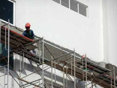 Kuala Lumpur, Malezya-23 Temmuz 2018: inşaat işçileri çimento kullanarak duvar sıvama alçı inşaat alanında. Onlar kötü olmasını önlemek için uygun güvenlik dişli giyiyorsun. 