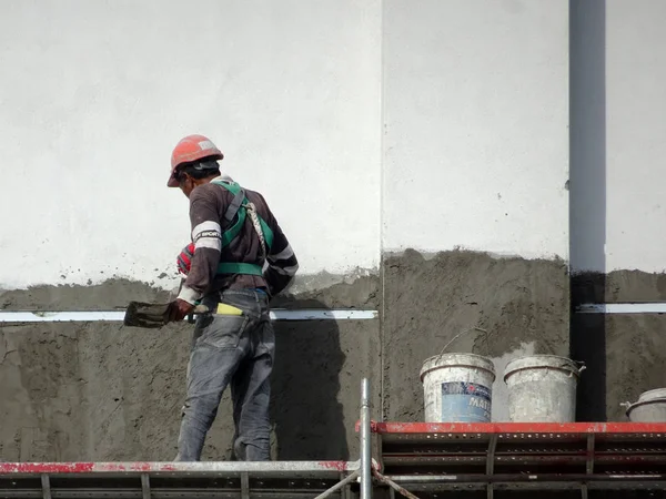 Kuala Lumpur, Malezya-23 Temmuz 2018: inşaat işçileri çimento kullanarak duvar sıvama alçı inşaat alanında. Onlar kötü olmasını önlemek için uygun güvenlik dişli giyiyorsun. 