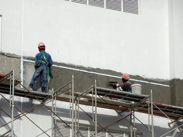 Kuala Lumpur, Malezya-23 Temmuz 2018: inşaat işçileri çimento kullanarak duvar sıvama alçı inşaat alanında. Onlar kötü olmasını önlemek için uygun güvenlik dişli giyiyorsun. 