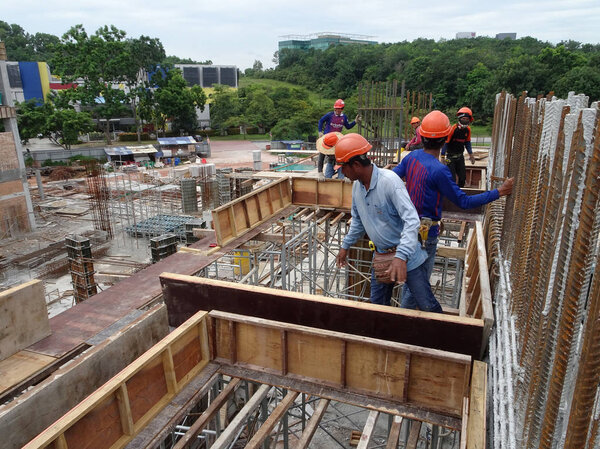 KUALA LUMPUR, MALAYSIA -JUNE 14, 2018: Construction workers fabricating timber plywood form works at the construction site. The timber form work used as the temporary reinforcement concrete mold.  