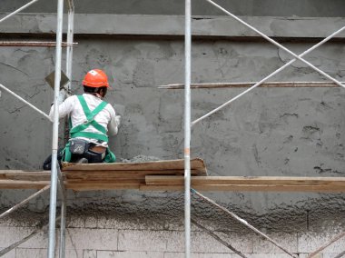 Kuala Lumpur, Malezya-23 Ağustos 2018: çimento alçı kullanarak inşaat işçileri tarafından sıvalı tuğla duvar. İskele geçici evreleme olarak yükseklikte çalışırdım. Kötü olmasını önlemek için uygun güvenlik dişli giyiyor.  