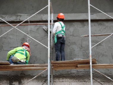 Kuala Lumpur, Malezya-23 Ağustos 2018: çimento alçı kullanarak inşaat işçileri tarafından sıvalı tuğla duvar. İskele geçici evreleme olarak yükseklikte çalışırdım. Kötü olmasını önlemek için uygun güvenlik dişli giyiyor.  