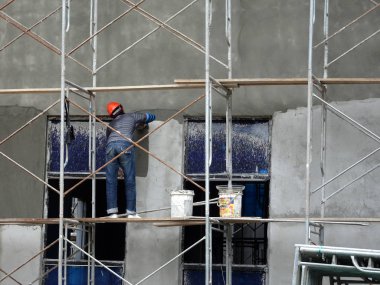 Kuala Lumpur, Malezya-23 Ağustos 2018: çimento alçı kullanarak inşaat işçileri tarafından sıvalı tuğla duvar. İskele geçici evreleme olarak yükseklikte çalışırdım. Kötü olmasını önlemek için uygun güvenlik dişli giyiyor.  