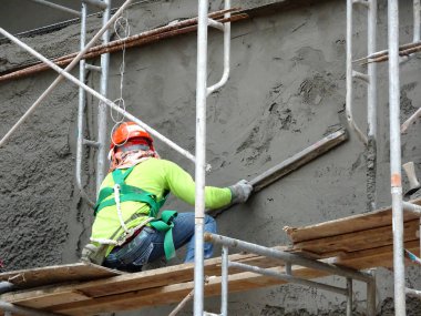 Kuala Lumpur, Malezya-23 Ağustos 2018: çimento alçı kullanarak inşaat işçileri tarafından sıvalı tuğla duvar. İskele geçici evreleme olarak yükseklikte çalışırdım. Kötü olmasını önlemek için uygun güvenlik dişli giyiyor.  