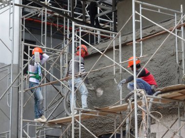 Kuala Lumpur, Malezya-23 Ağustos 2018: çimento alçı kullanarak inşaat işçileri tarafından sıvalı tuğla duvar. İskele geçici evreleme olarak yükseklikte çalışırdım. Kötü olmasını önlemek için uygun güvenlik dişli giyiyor.  