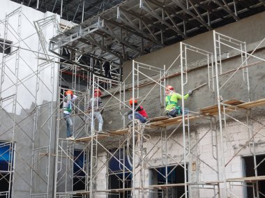 Kuala Lumpur, Malezya-23 Ağustos 2018: çimento alçı kullanarak inşaat işçileri tarafından sıvalı tuğla duvar. İskele geçici evreleme olarak yükseklikte çalışırdım. Kötü olmasını önlemek için uygun güvenlik dişli giyiyor.  