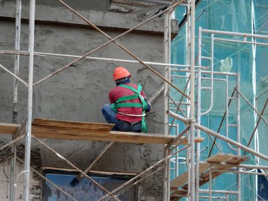 Kuala Lumpur, Malezya-23 Ağustos 2018: çimento alçı kullanarak inşaat işçileri tarafından sıvalı tuğla duvar. İskele geçici evreleme olarak yükseklikte çalışırdım. Kötü olmasını önlemek için uygun güvenlik dişli giyiyor.  