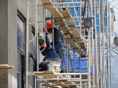 Kuala Lumpur, Malezya-23 Ağustos 2018: çimento alçı kullanarak inşaat işçileri tarafından sıvalı tuğla duvar. İskele geçici evreleme olarak yükseklikte çalışırdım. Kötü olmasını önlemek için uygun güvenlik dişli giyiyor.  