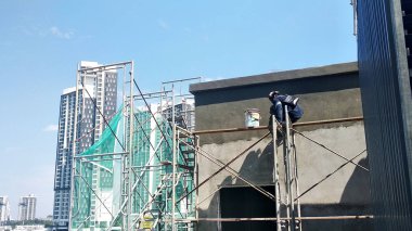 Kuala Lumpur, Malezya-23 Ağustos 2018: çimento alçı kullanarak inşaat işçileri tarafından sıvalı tuğla duvar. İskele geçici evreleme olarak yükseklikte çalışırdım. Kötü olmasını önlemek için uygun güvenlik dişli giyiyor.  