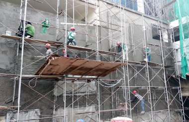 Kuala Lumpur, Malezya-23 Ağustos 2018: çimento alçı kullanarak inşaat işçileri tarafından sıvalı tuğla duvar. İskele geçici evreleme olarak yükseklikte çalışırdım. Kötü olmasını önlemek için uygun güvenlik dişli giyiyor.  