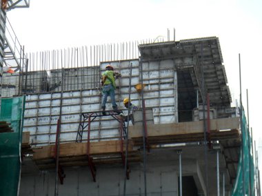 Kuala Lumpur, Malezya-10 Ağustos 2017: inşaat işçileri yükseklikte inşaat alanında çalışıyor. Onlar kötü olur etmelerini önlemek için uygun güvenlik dişli giymek için rica olunur. 