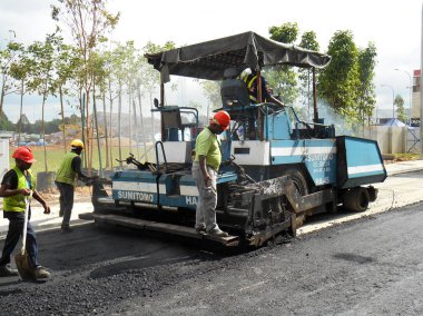 Kuala Lumpur, Malezya-15 Mayıs 2017: Premix iş inşaat işçileri tarafından. İşçiler tarafından tesviye ve kompaktör makine tarafından sıkıştırılmış asfalt katmanı. 