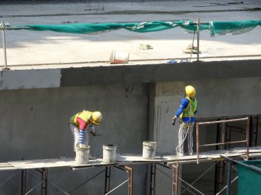 Kuala Lumpur, Malezya-23 Ağustos 2018: çimento alçı kullanarak inşaat işçileri tarafından sıvalı tuğla duvar. İskele geçici evreleme olarak yükseklikte çalışırdım. Kötü olmasını önlemek için uygun güvenlik dişli giyiyor.  