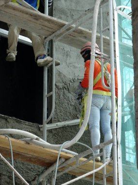 Kuala Lumpur, Malezya-23 Ağustos 2018: çimento alçı kullanarak inşaat işçileri tarafından sıvalı tuğla duvar. İskele geçici evreleme olarak yükseklikte çalışırdım. Kötü olmasını önlemek için uygun güvenlik dişli giyiyor.  